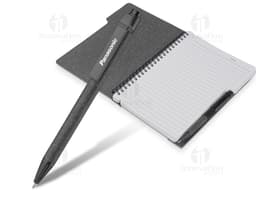 Caderno em branco aberto sobre a mesa de escritório, com uma caneta ao lado. O caderno tem capa de couro preta, folhas em