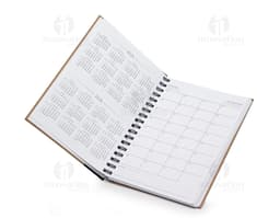 Caderno de capa kraft aberto, com páginas em branco e caneta sobre a mesa de escritório. Na página, há anotações sobre