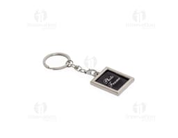 Chaveiro de metal em formato de corrente com chave, amuleto e outros objetos pendurados. Feito em prata e ouro, com design