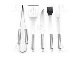 Kit Churrasco 5 Peças - Conjunto contendo faca, garfo, pinça, espátula e escova para churrasco em fundo de madeira.
