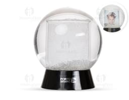 Globo de neve plástico transparente com uma paisagem de neve e uma pequena figura de um boneco de neve no centro.