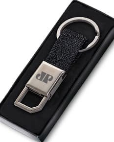 Chaveiro de couro preto com detalhes em metal prateado. Possui um suporte para celular e uma ferramenta cortante embutida. O