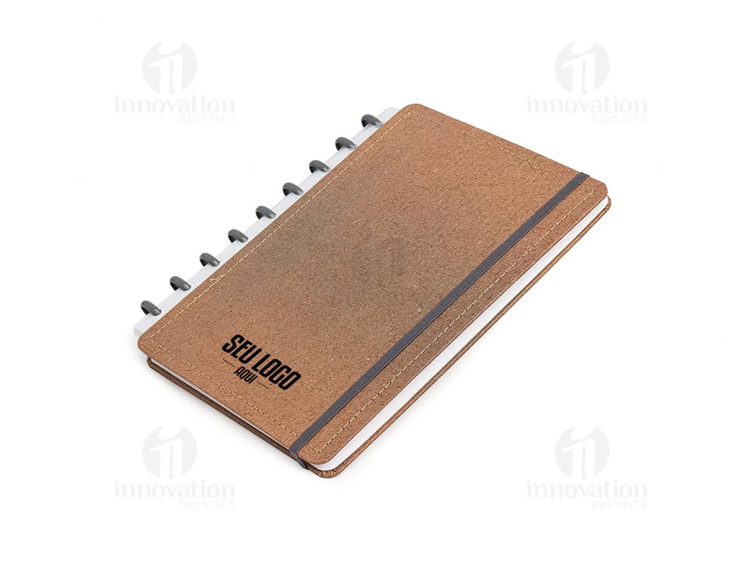 Caderno de disco Percalux marrom com capa de couro, aberto, contendo folhas em branco e um lápis antigo.