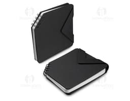 Mini caderno preto de couro aberto sobre uma mesa de escritório, ao lado de um notebook e diversos dispositivos eletrônicos.