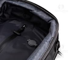 Homem de negócios sorridente e bem vestido segurando uma mochila de couro preta. Ele está de pé em um estúdio e parece feliz