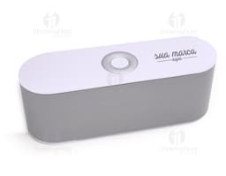 Caixa de som Bluetooth em metal prateado, moderna, com design clean. Contém botões de controle, entrada para cartão e conexão