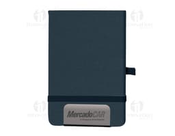Mini Caderno marrom de couro, aberto, com página em branco. Ao lado, um pen drive, um chaveiro, um diário preto e um celular.