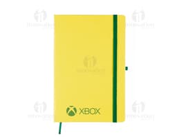 Notebook amarelo aberto com papel pautado em um escritório, ao lado de um modem, um telefone e um copo de bebida.