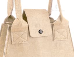 Bolsa de feltro marrom com fecho de metal, alça de couro e detalhes em etiqueta de papel. O produto mostra elegância e