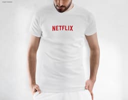 Homem jovem e atraente usando uma camiseta preta tradicional, sorrindo de forma confiante e casual. Ele está em pé, posando