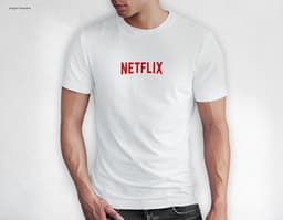 Homem jovem e atraente sorrindo, posando em um estúdio com uma camiseta preta de algodão tradicional de 165g/m². Ele está