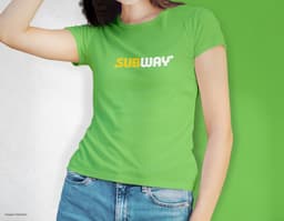 Camiseta feminina de corte cinturado em cor azul, usada por uma modelo sorridente e atraente. Ela está posando de forma