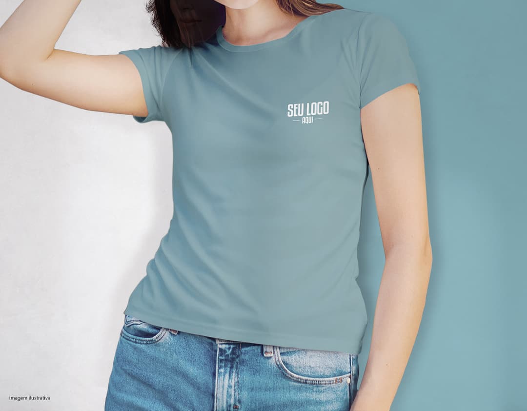Camiseta feminina de corte cinturado em cor azul, usada por uma modelo sorridente e atraente. Ela está posando de forma