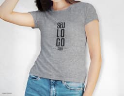 Camiseta feminina de corte cinturado em cor azul, usada por uma modelo sorridente e atraente. Ela está posando de forma