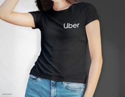 Camiseta feminina de corte cinturado em cor azul, usada por uma modelo sorridente e atraente. Ela está posando de forma