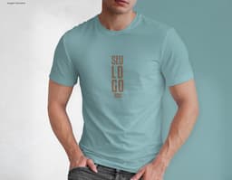 Homem jovem e atraente posando de maneira casual com uma camiseta de algodão tradicional. Ele está sorrindo e tem um sorriso