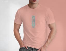 Homem jovem e atraente posando de maneira casual com uma camiseta de algodão tradicional. Ele está sorrindo e tem um sorriso