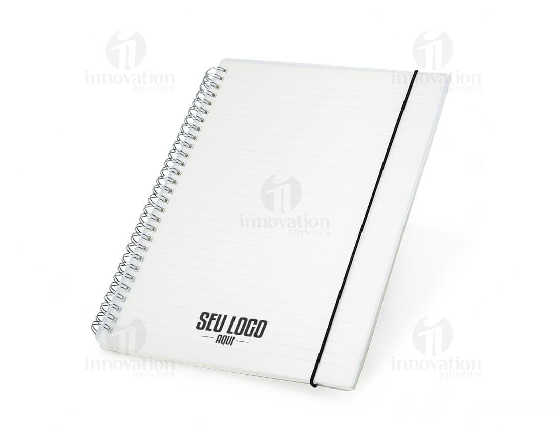 Notebook B5 Plástico 26x19 em fundo branco aberto, com papel em branco e envelope ao lado. Objeto de estudo e organização