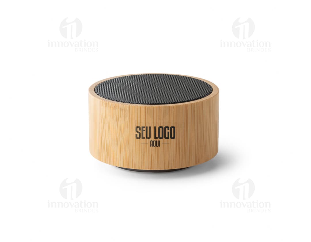 : Caixa de som de bambu e ABS com Bluetooth versão 5.0 em close-up, sobre um bloco de corte. O objeto é metálico, de cor