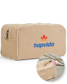 Bolsa de cosméticos marrom e preta, vazia, com fecho de zíper. Ao redor, encontram-se diversos objetos como um carimbo, um