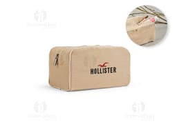 Bolsa de cosméticos marrom e preta, vazia, com fecho de zíper. Ao redor, encontram-se diversos objetos como um carimbo, um