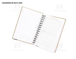 Foto de uma agenda diária para o ano de 2025, com capa marrom e textura de papel antigo. A agenda possui espiral, páginas em