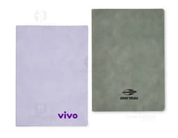 Caderno B5 PU preto sobre uma mesa de escritório, ao lado de um laptop, teclado, mouse e disco de vídeo. A imagem também