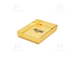 Caixa de presente na cor vermelha, com laço dourado e pequenos detalhes brilhantes.